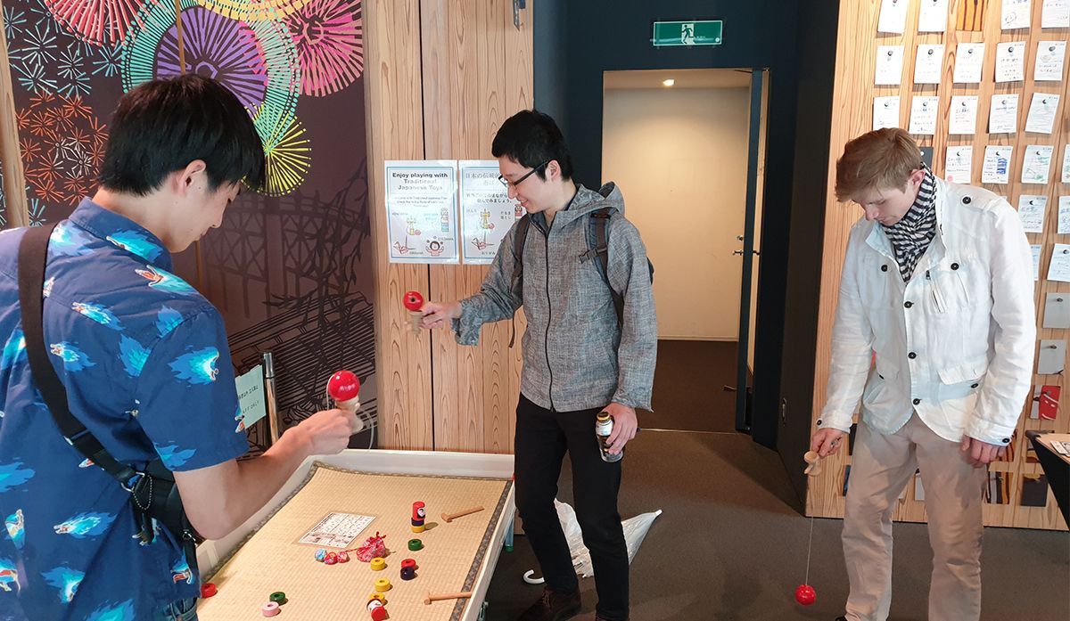Three language students play with japanese traditional kendama