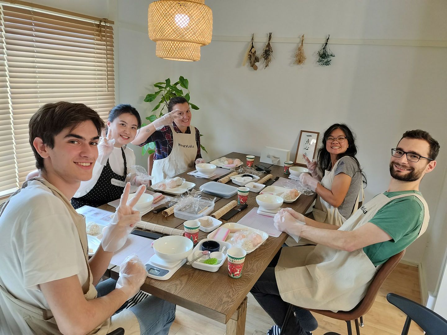 Five language students sit at a table participating on japanese cooking workshop