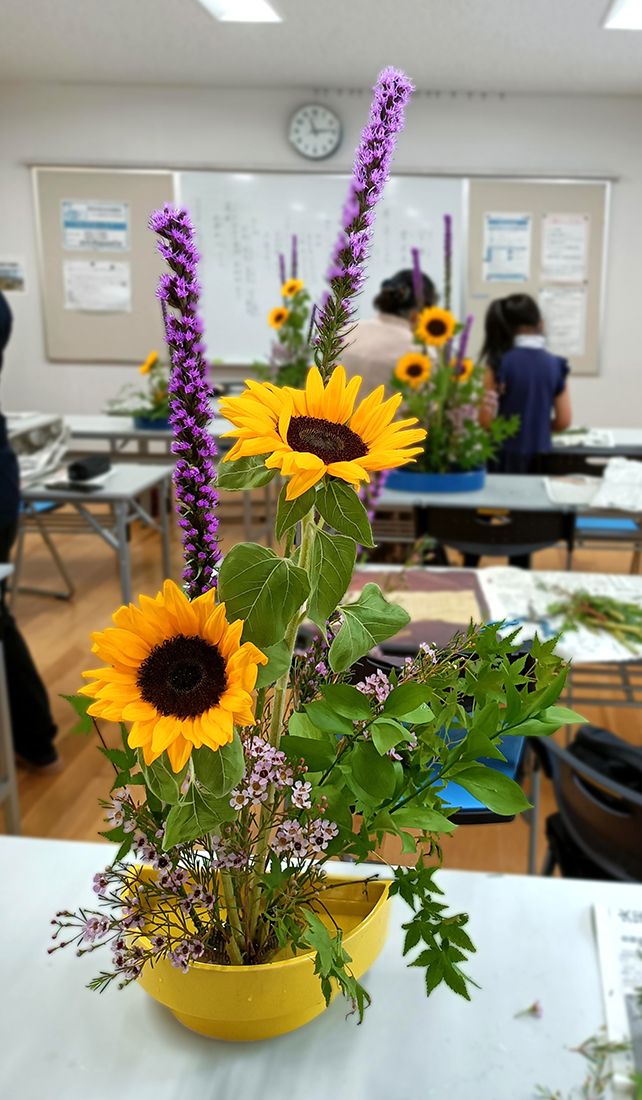 A yellow flower on a table in a language school classroom
