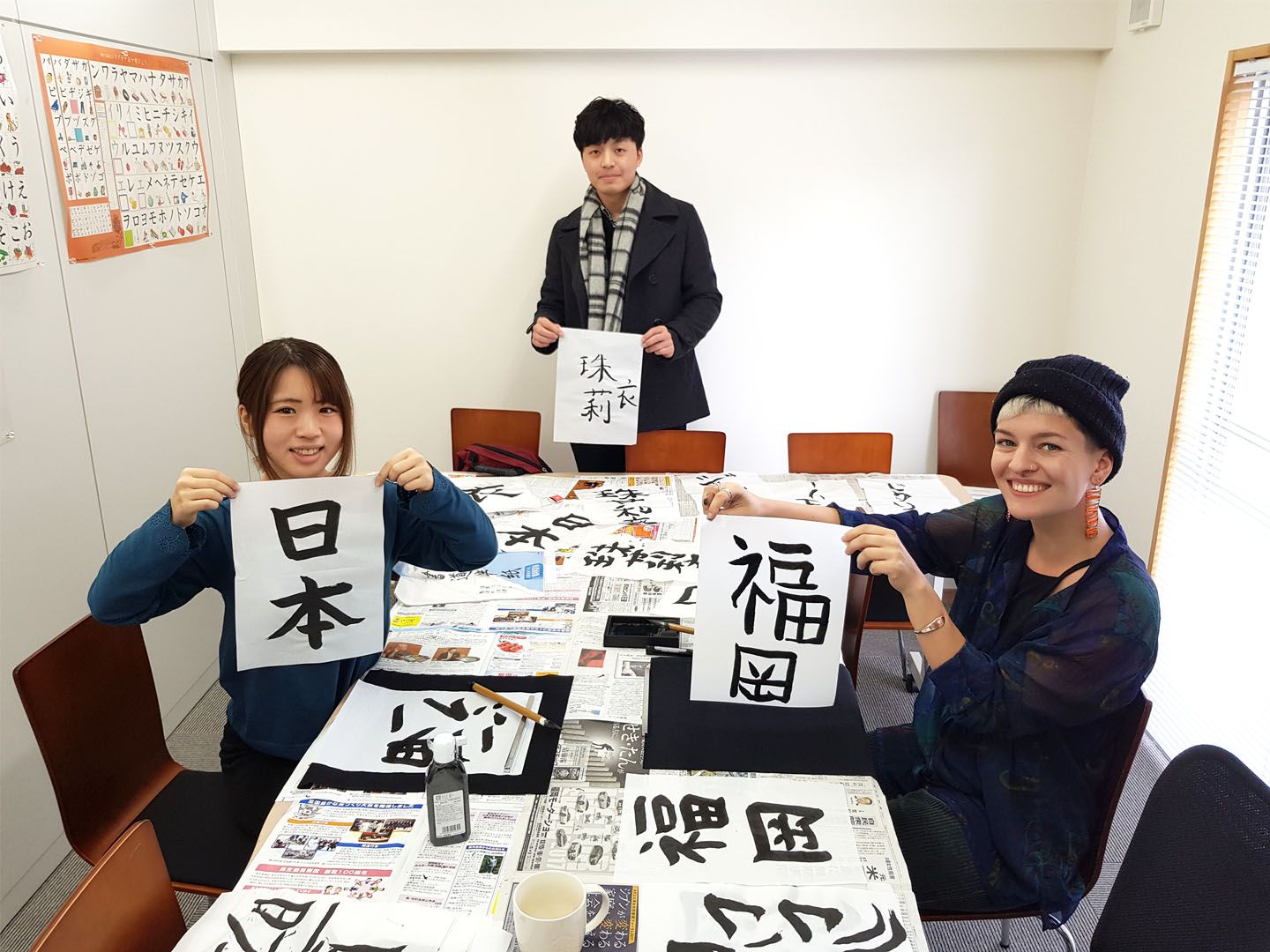 Two language students drawing japanese kanji with traditional ink