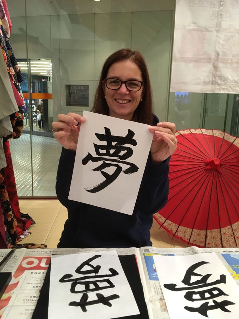 Two language students drawing japanese kanji with traditional ink