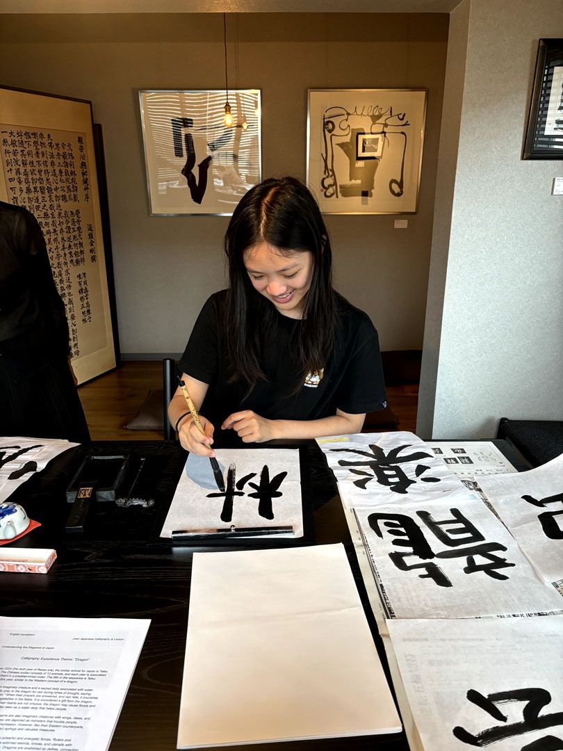 Two language students drawing japanese kanji with traditional ink