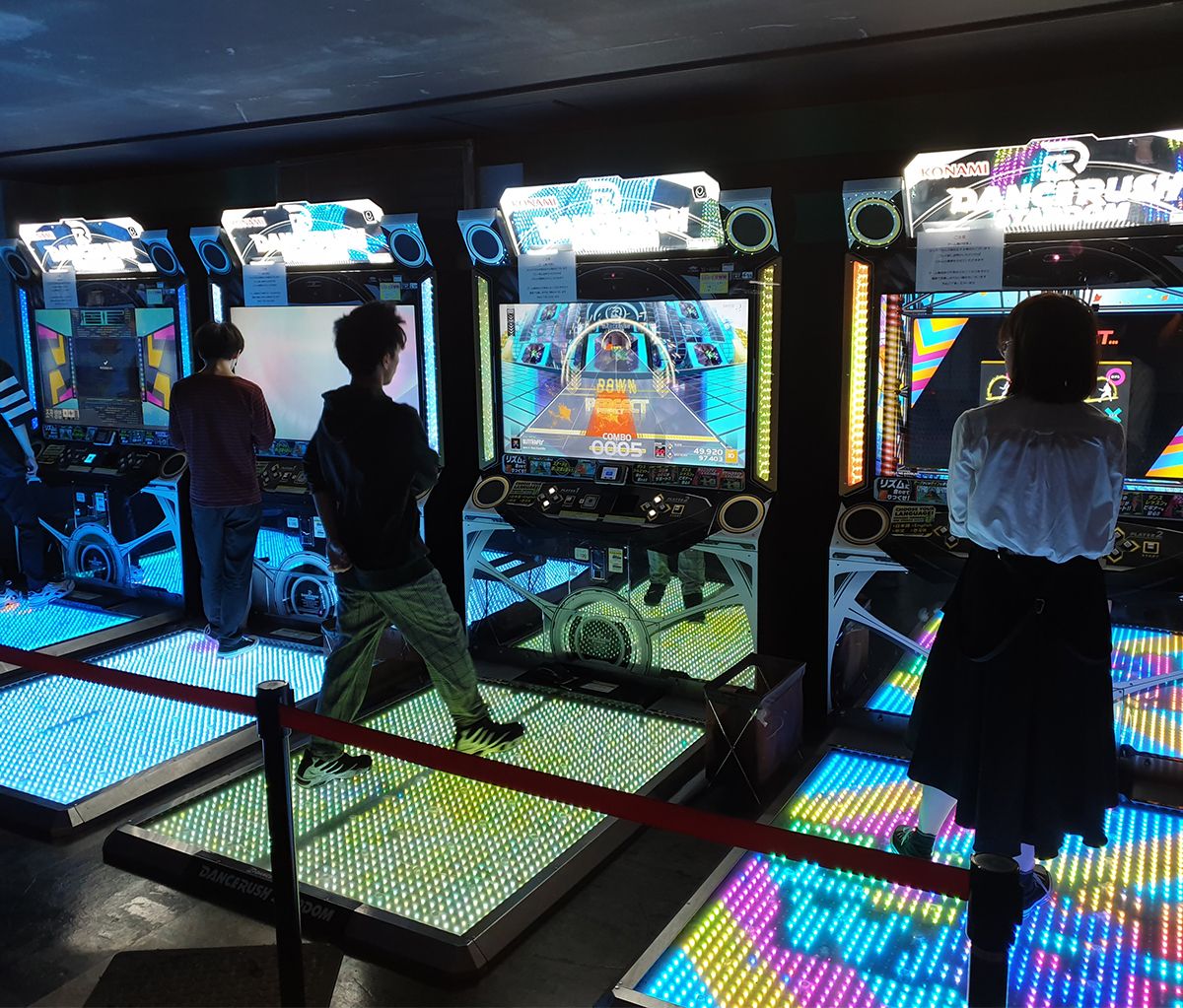 Language students playing dancing games in a japanese arcade hall