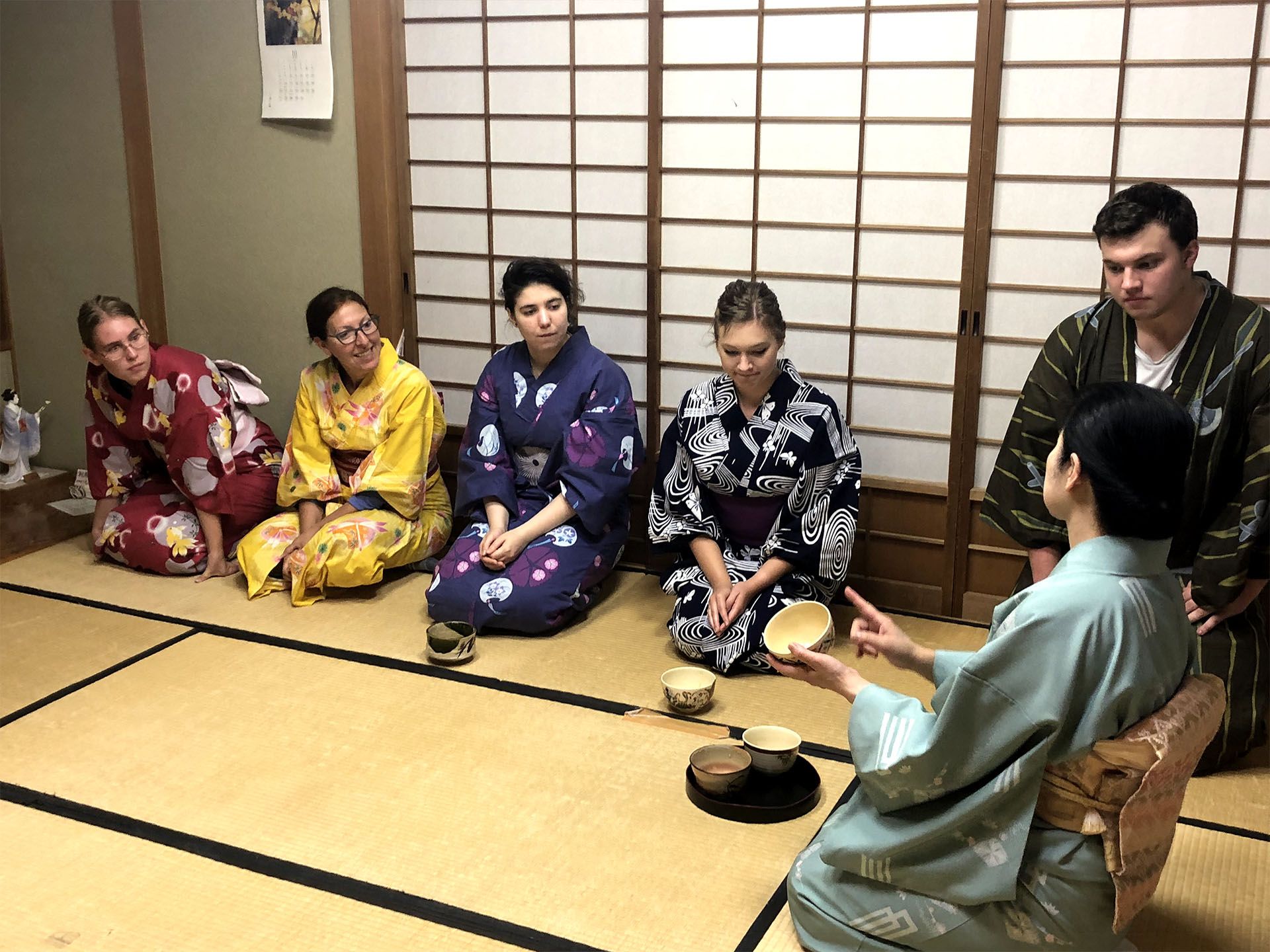 Language students drinking traditional japanese tea, wearing a kimono