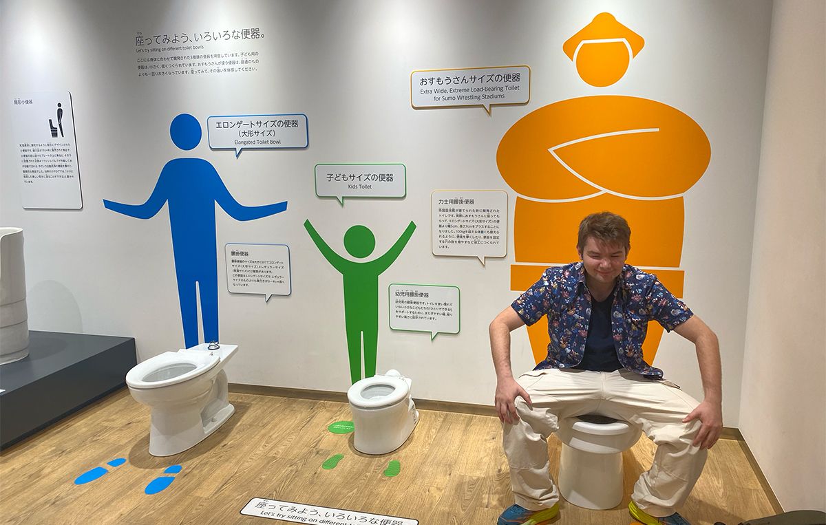 Language student sitting on a display toilet in a toilet museum