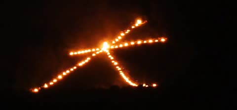 A large Japanese kanji character (大) formed by bonfires burns on a dark hillside against the night sky.