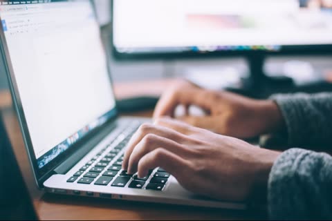 Person's hands typing on a laptop keyboard.