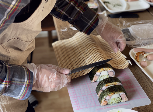 Language student is cutting and rolling self-made sushi